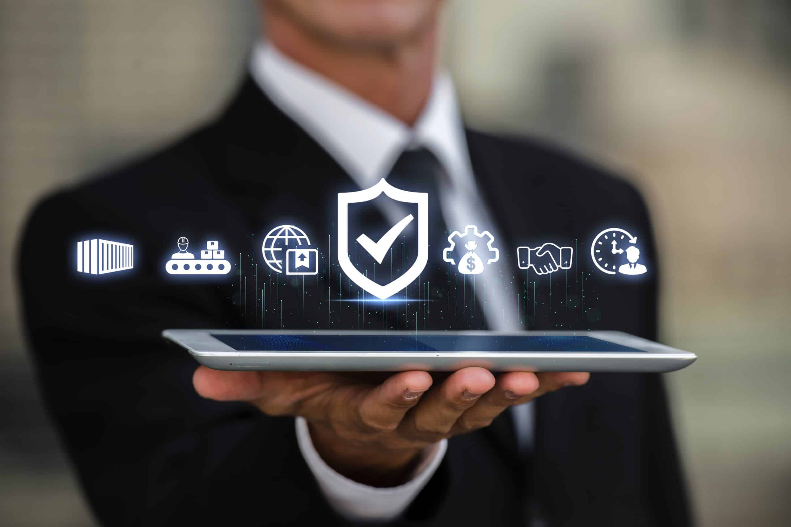 A man in a suit holds a tablet displaying a central shield with a checkmark, surrounded by glowing white icons representing quality control, supply chain management, global logistics, efficiency, and timely delivery.
